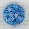 a bowl filled with blue glass beads on top of a wooden table