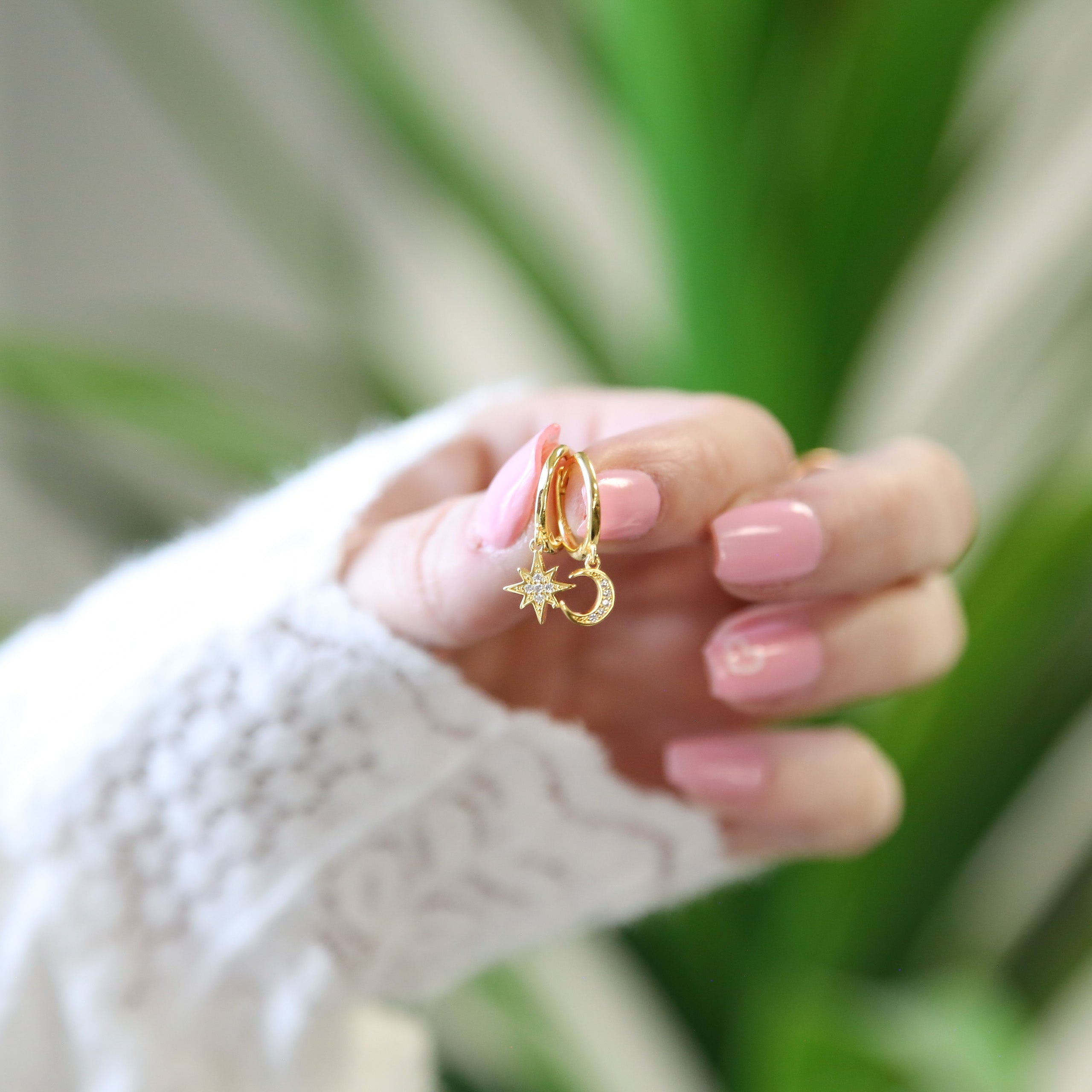 a woman's hand holding a pair of gold rings