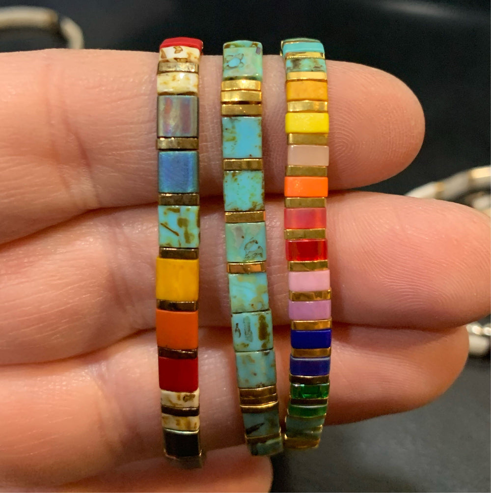 a person holding two colorful bracelets in their hand