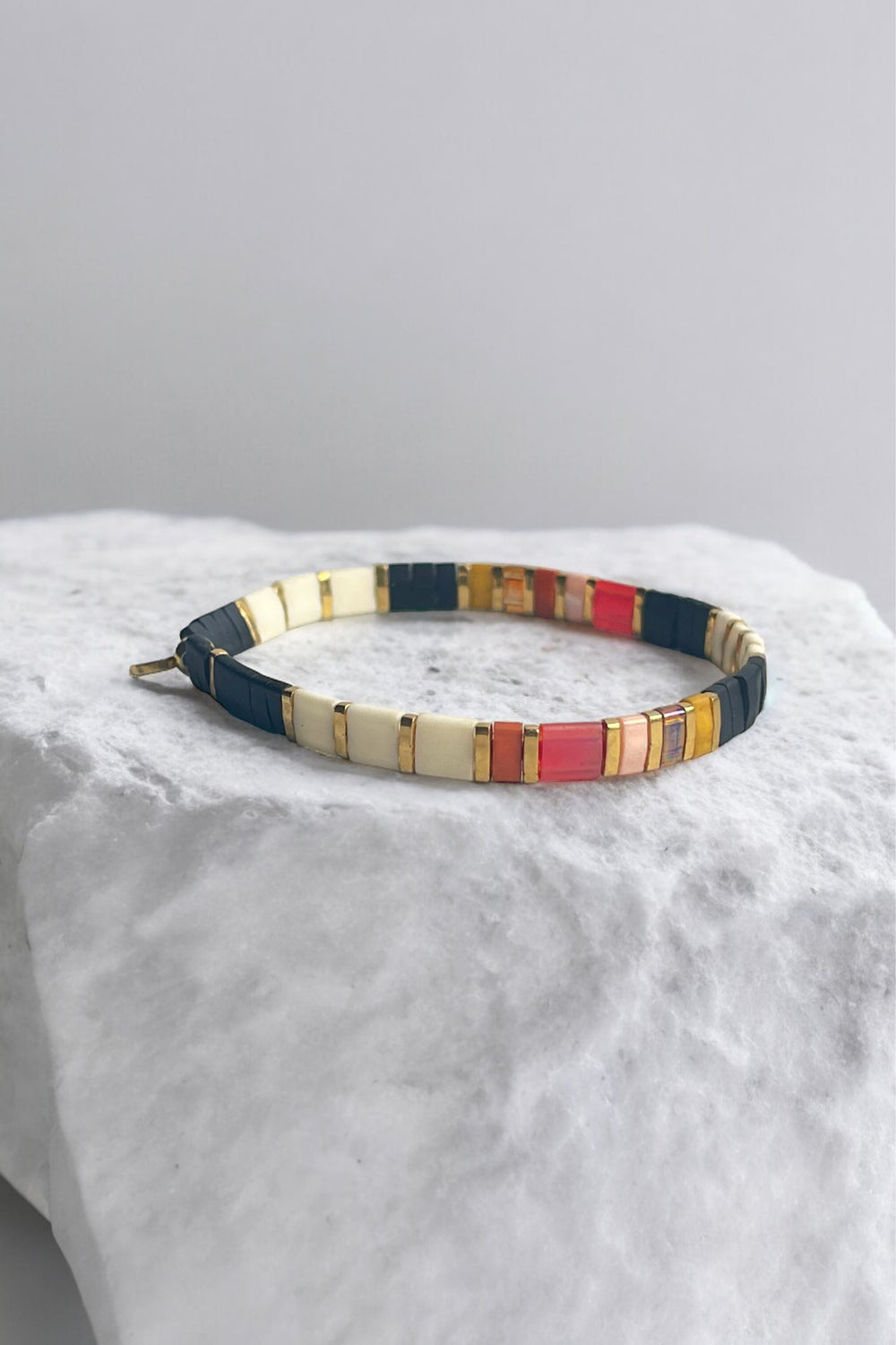 a pair of multicolored bracelets sitting on top of a rock