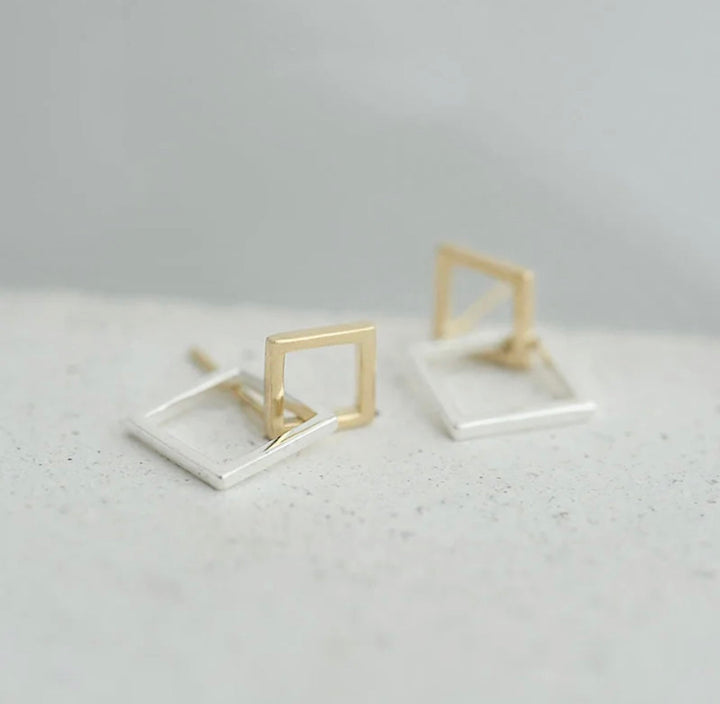 a pair of gold and silver square earrings