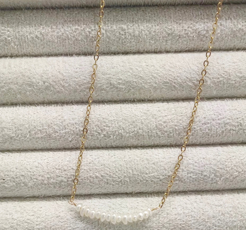 a gold chain with a white pearl on it