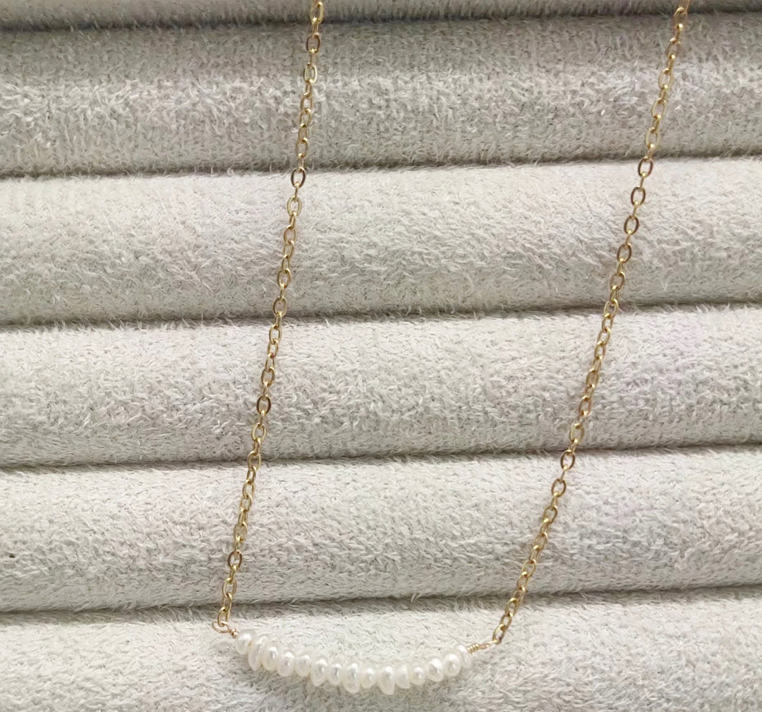 a gold chain with a white pearl on it
