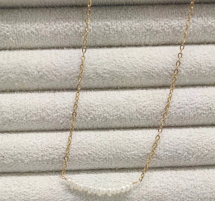 a gold chain with a white pearl on it