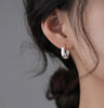 a woman wearing a pair of silver hoop earrings