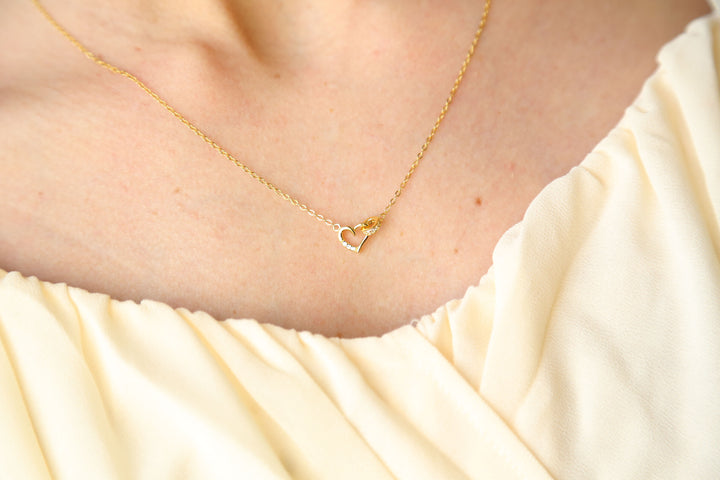a woman wearing a necklace with a heart on it