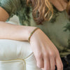 a woman sitting on a white couch with a bracelet on her wrist