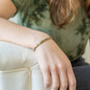 a woman sitting on a white couch wearing a bracelet