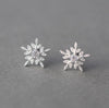 a pair of snowflake earrings sitting on top of a table