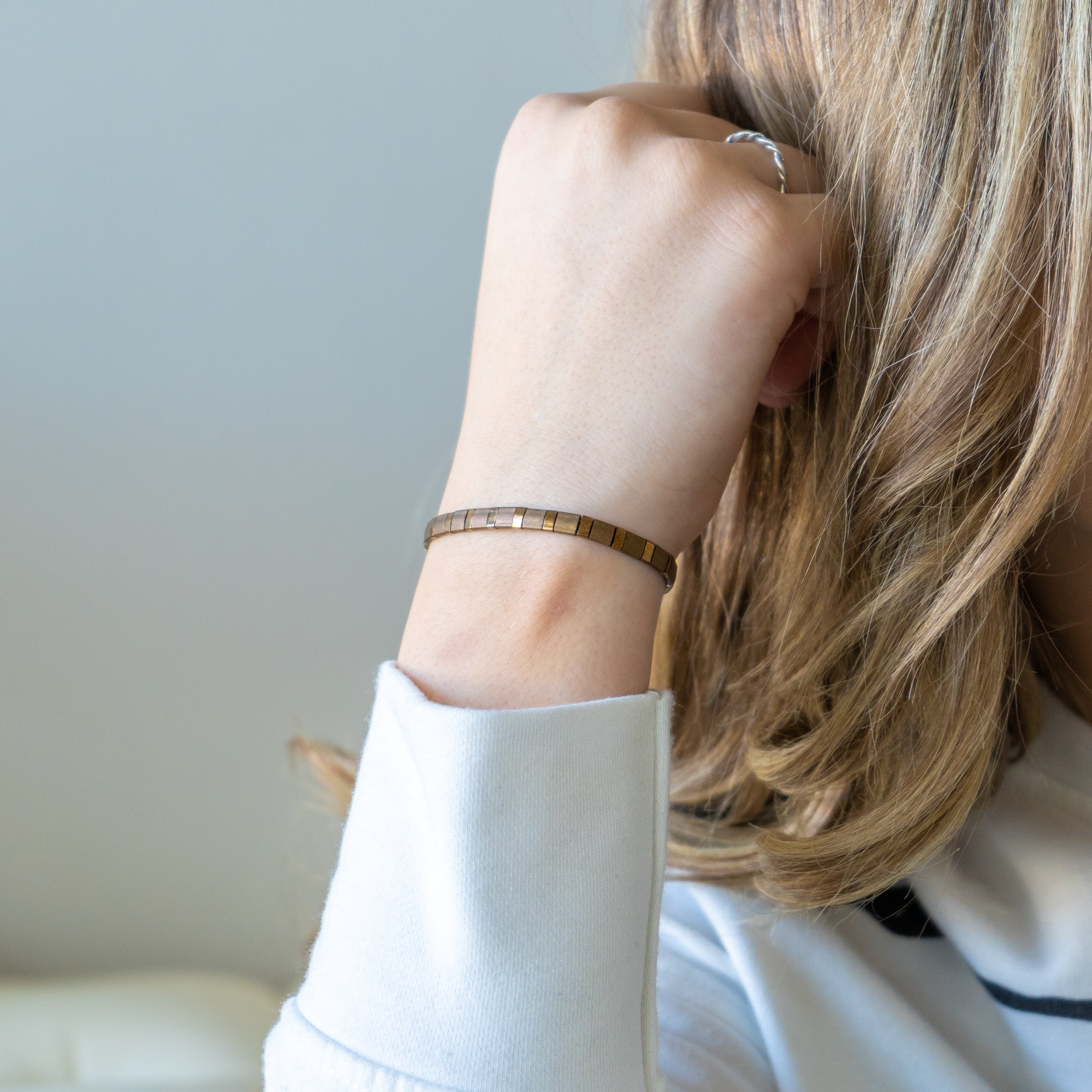 a woman wearing a white shirt and a gold bracelet