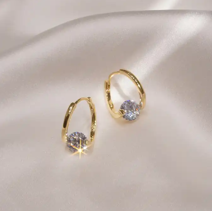 a pair of gold earrings on a white satin