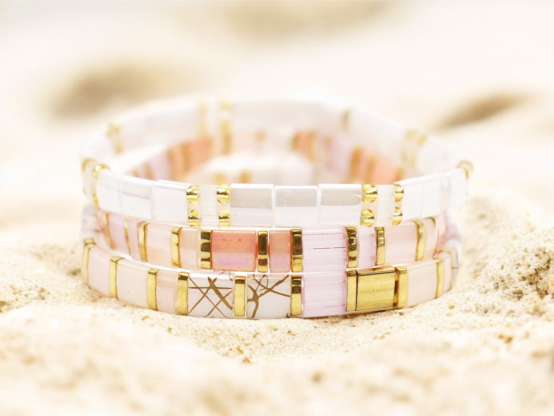 a couple of bracelets sitting on top of a sandy beach