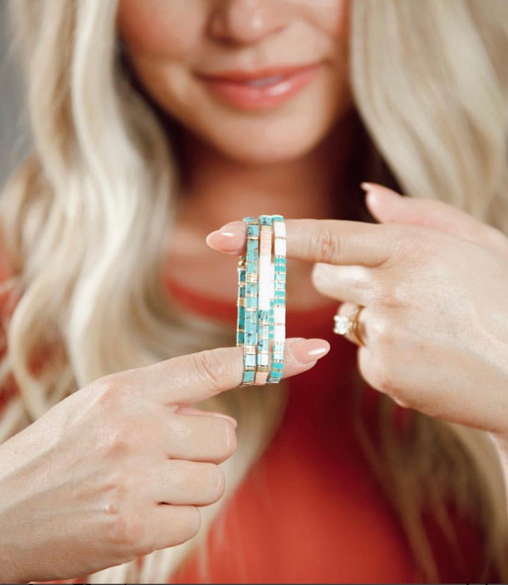 a woman wearing a ring with a turquoise and white pattern on it