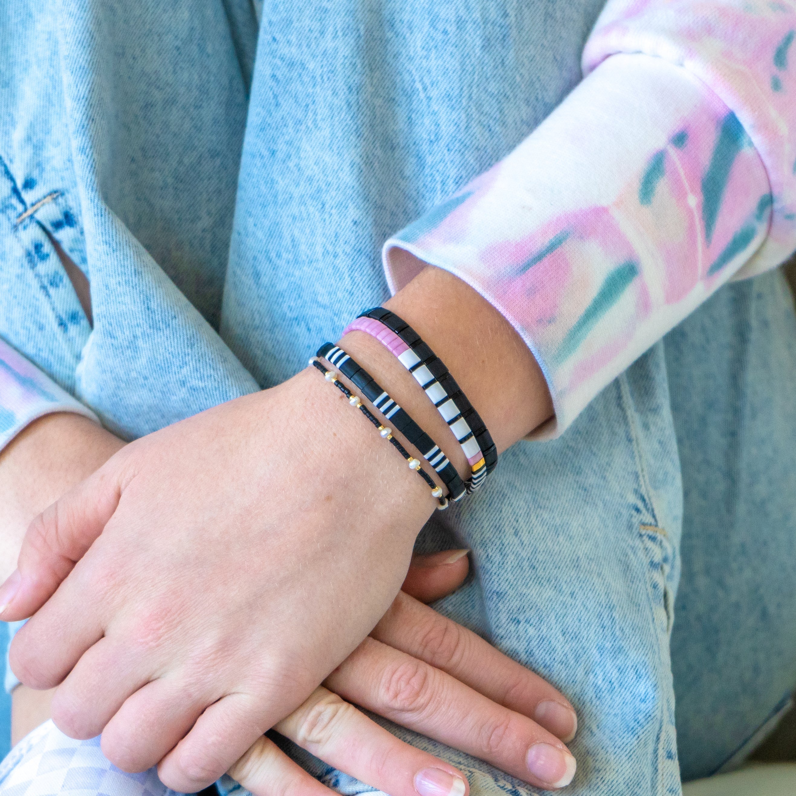 a person holding another person's hand with two bracelets on their wrists