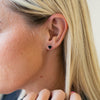 a woman wearing a pair of black diamond earrings