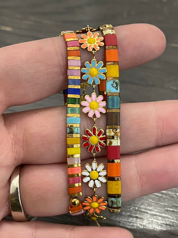 a person holding a colorful bracelet with flowers on it