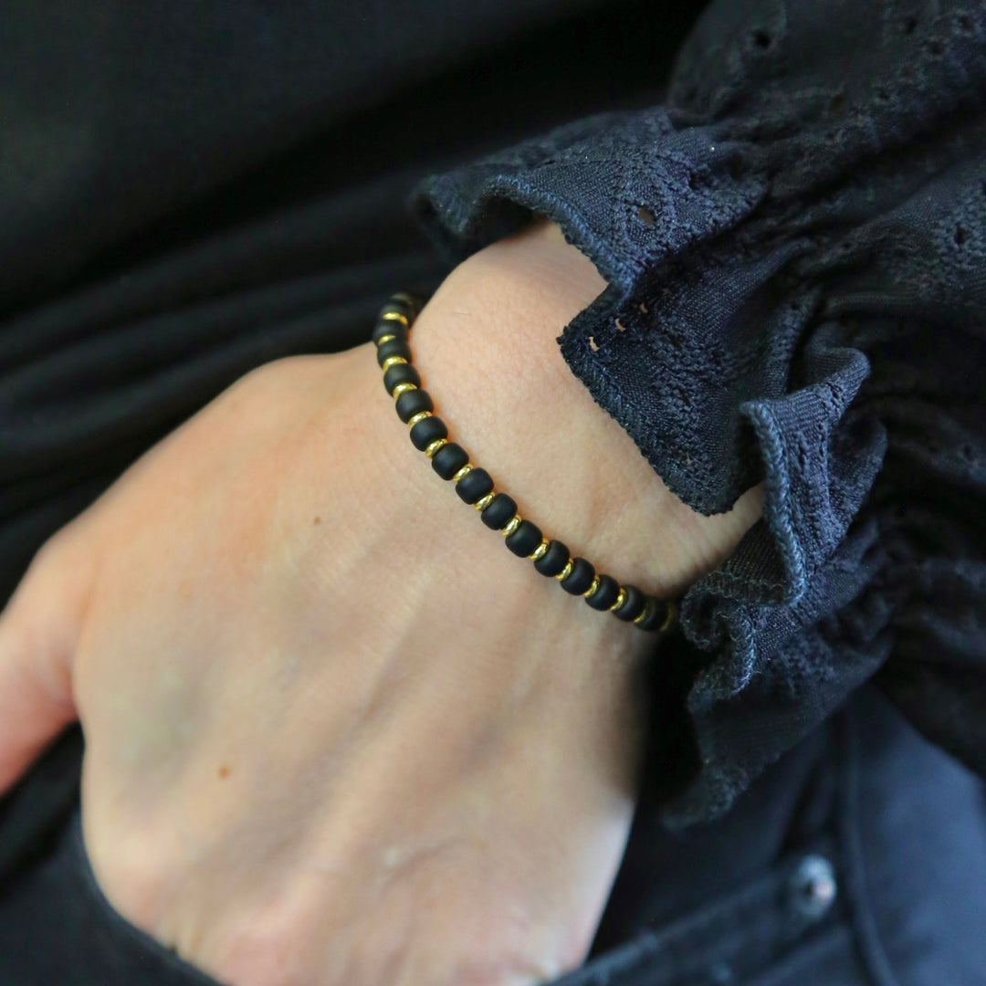 a person wearing a black and gold beaded bracelet