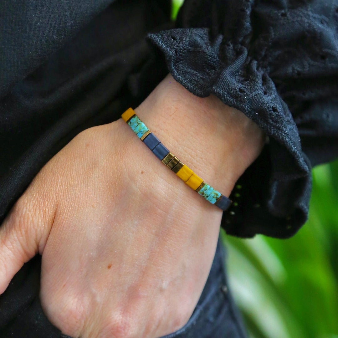 a person wearing a yellow and blue bracelet