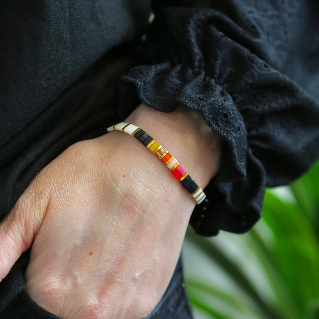 a person wearing a black jacket and a yellow and red bracelet