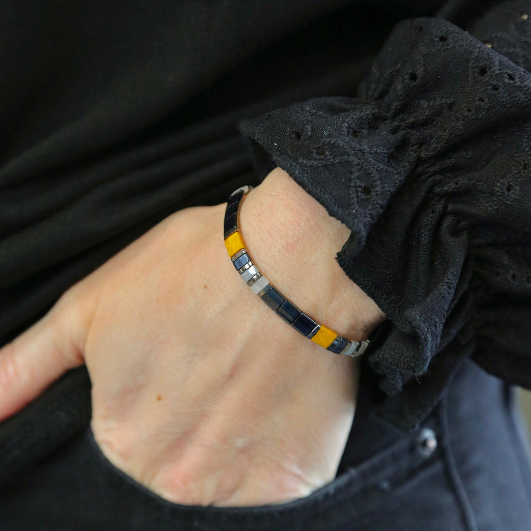 a person wearing a black and yellow bracelet