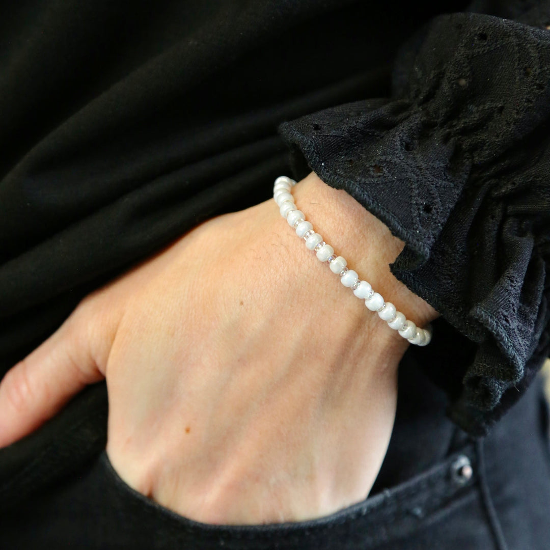 a person wearing a white beaded bracelet