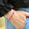 a woman wearing a red and pink bracelet