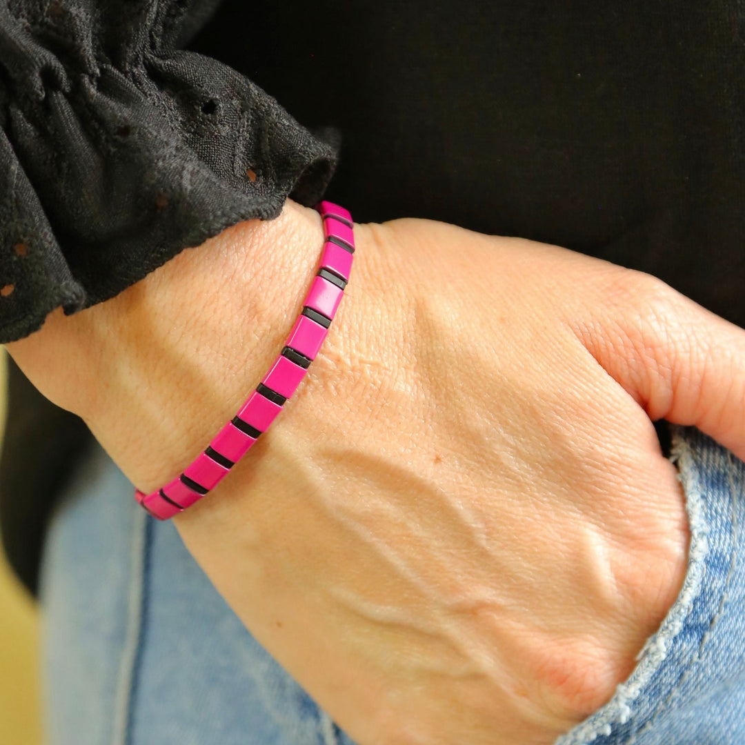 a person wearing a pink and black bracelet