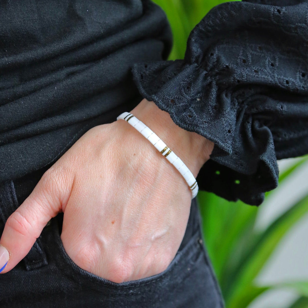 a woman's hand with a white bracelet on it