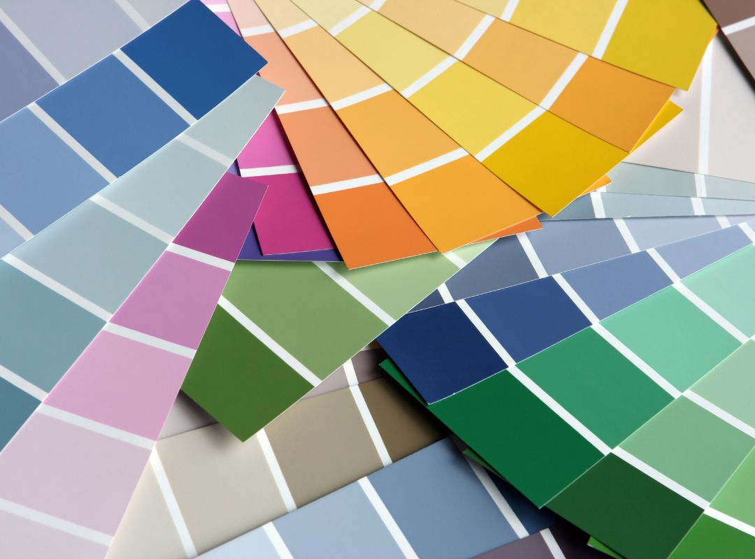 There are paint color swatch cards fanned out and the colors are yellows, blues, greens, and pinks.