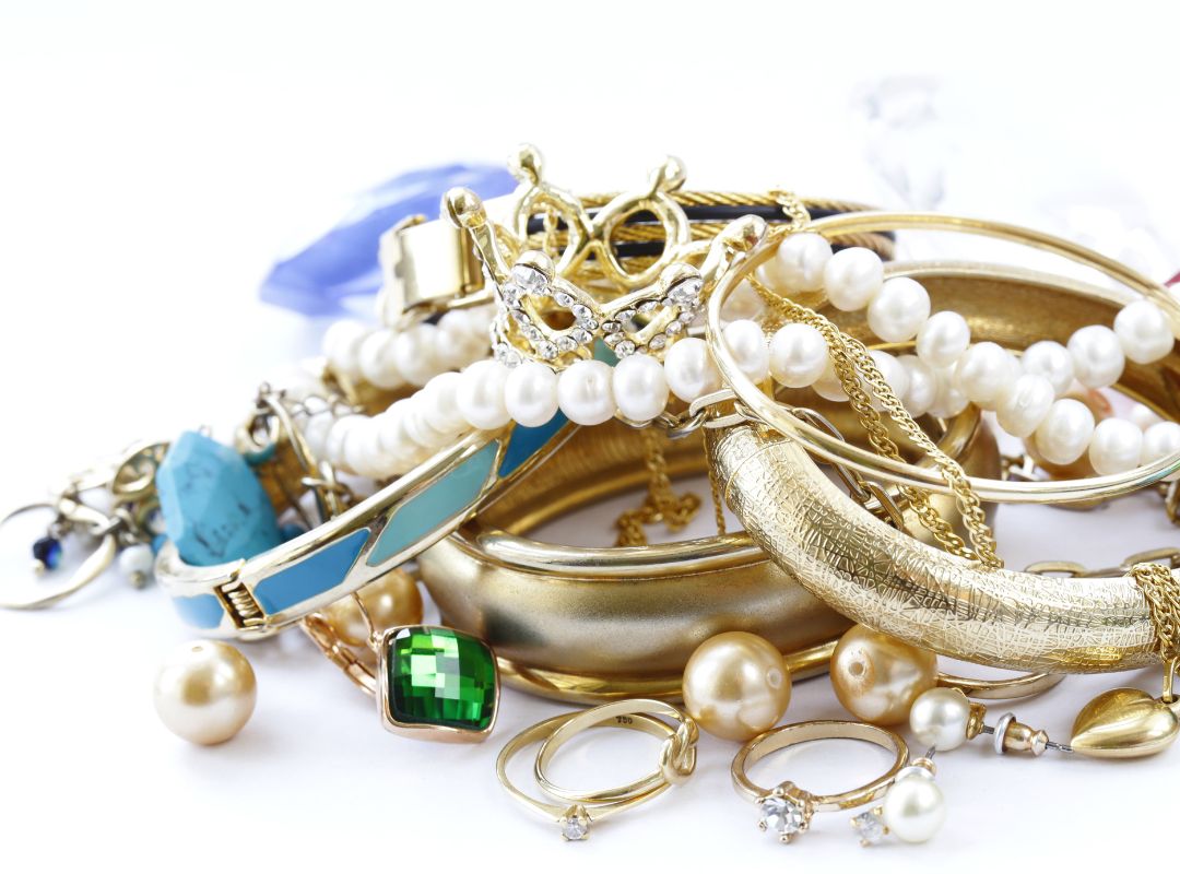 There is a pile of gold jewelry and pearls and other jewelry pieces.