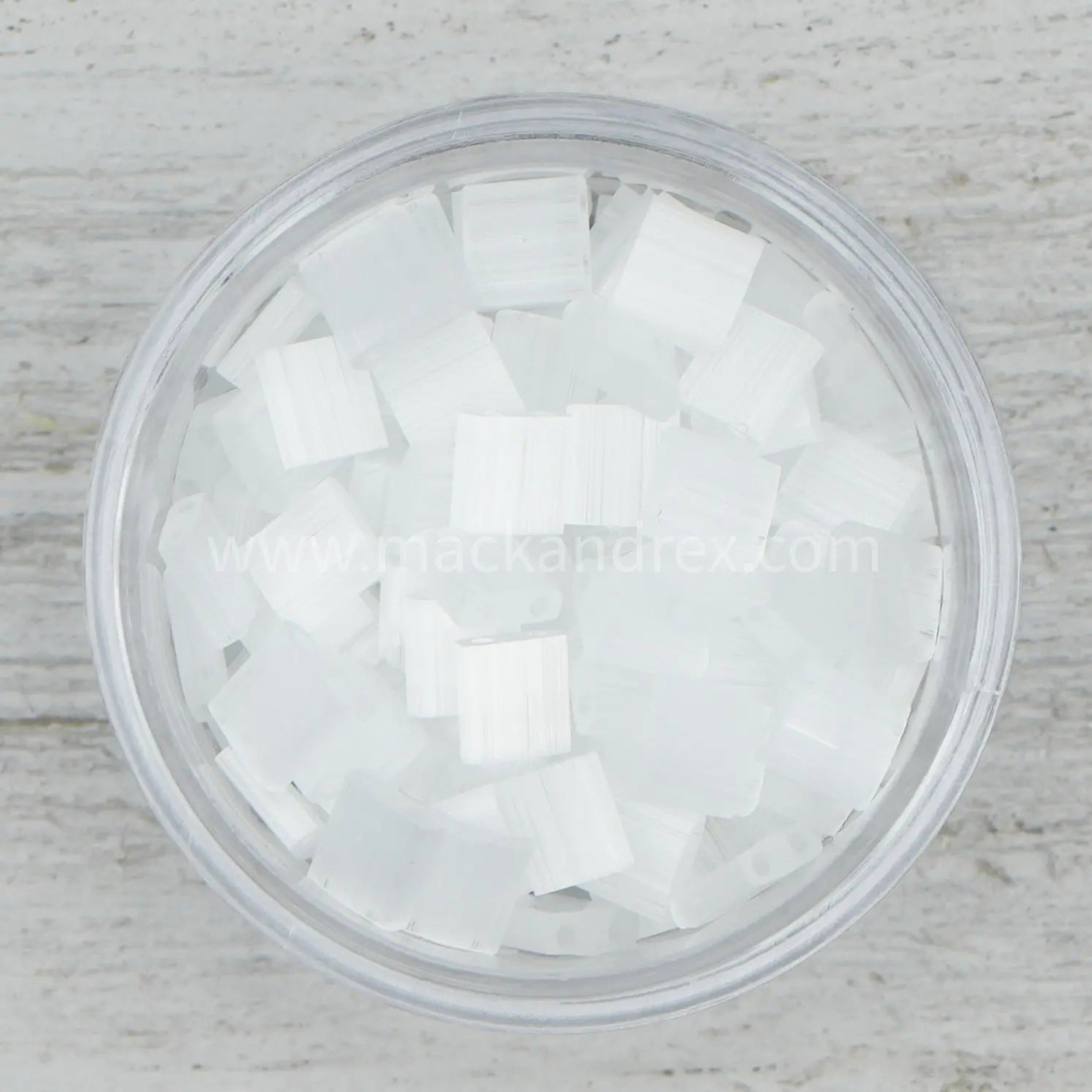 a glass filled with white sugar cubes on top of a wooden table