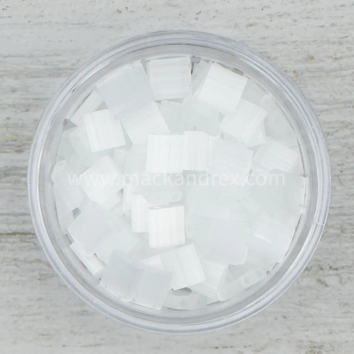 a glass filled with white sugar cubes on top of a wooden table