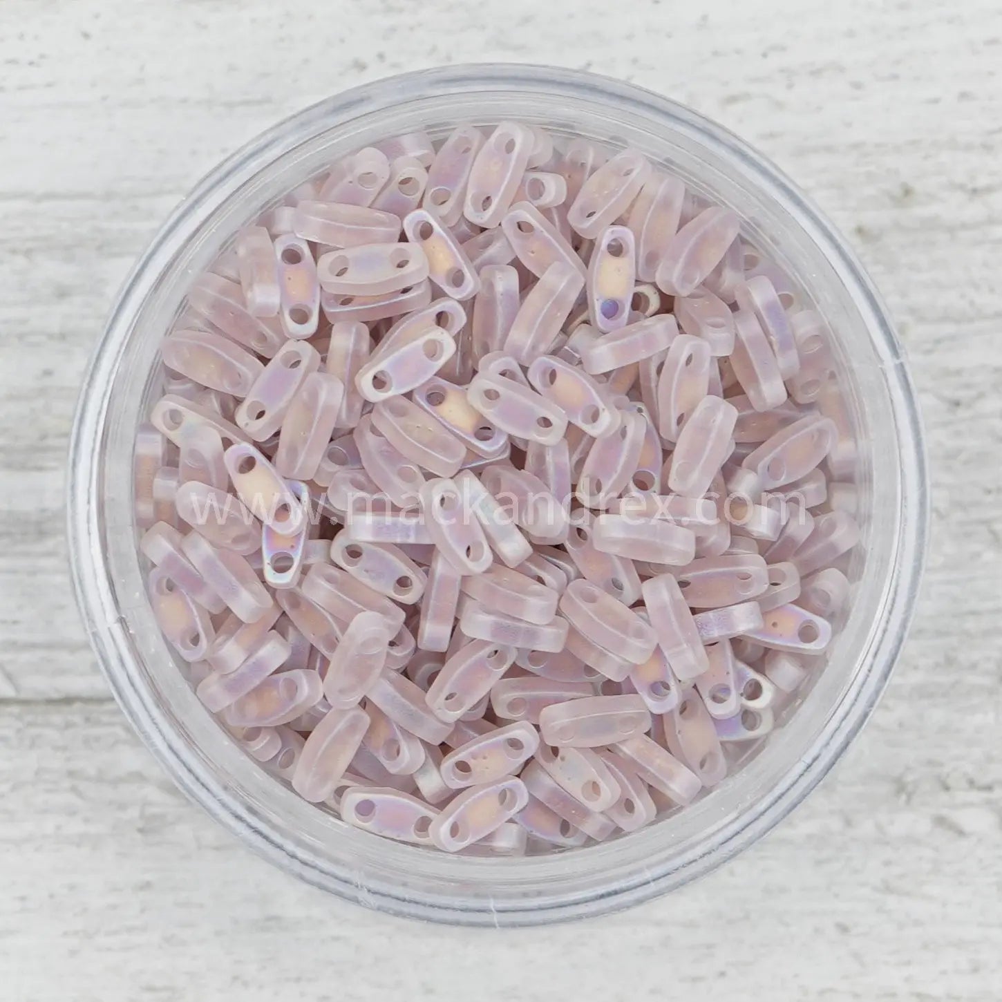 a bowl filled with pink beads on top of a wooden table