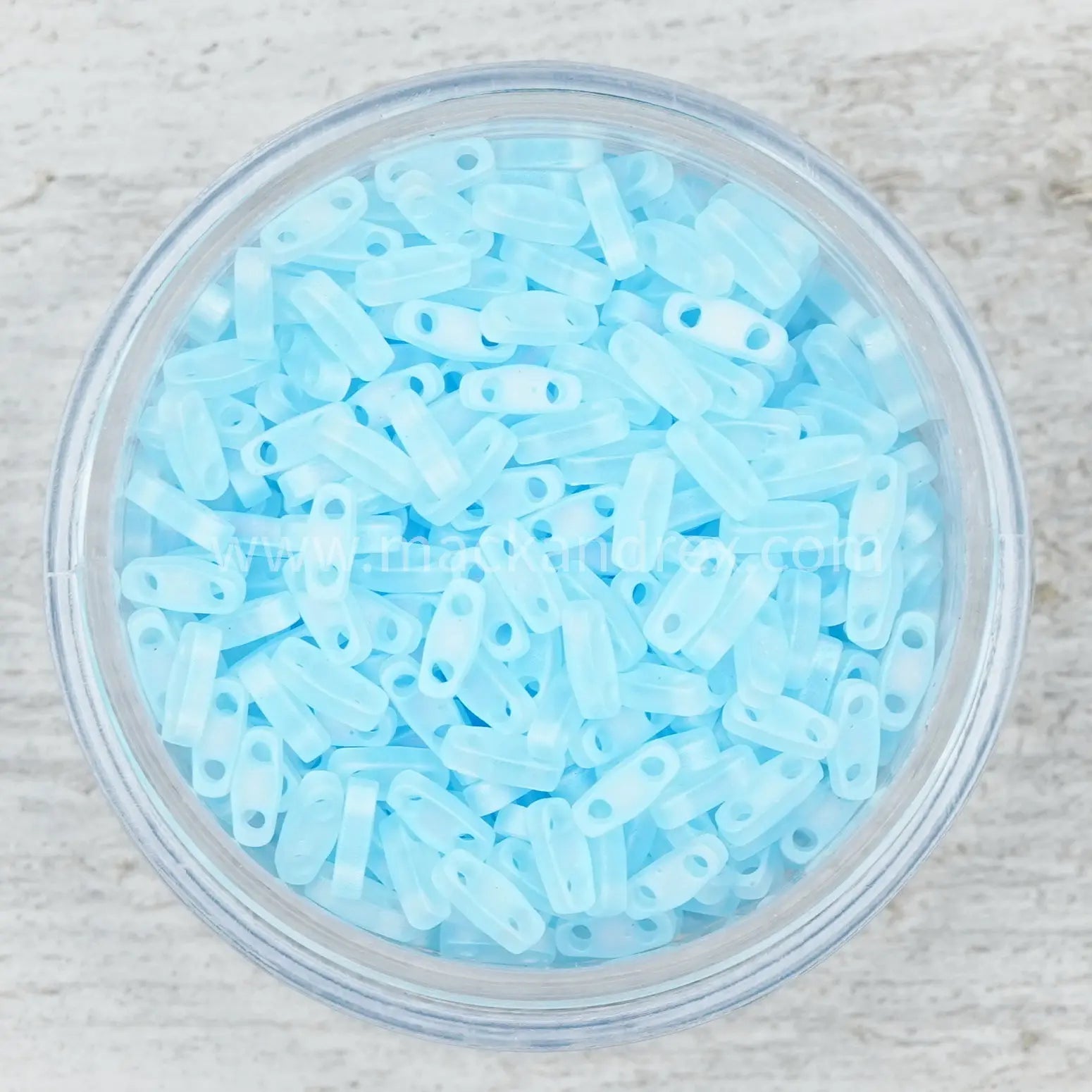 a bowl filled with blue plastic beads on top of a wooden table