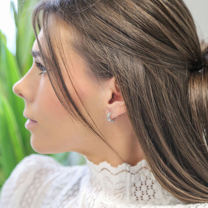 a woman with long hair wearing a pair of earrings