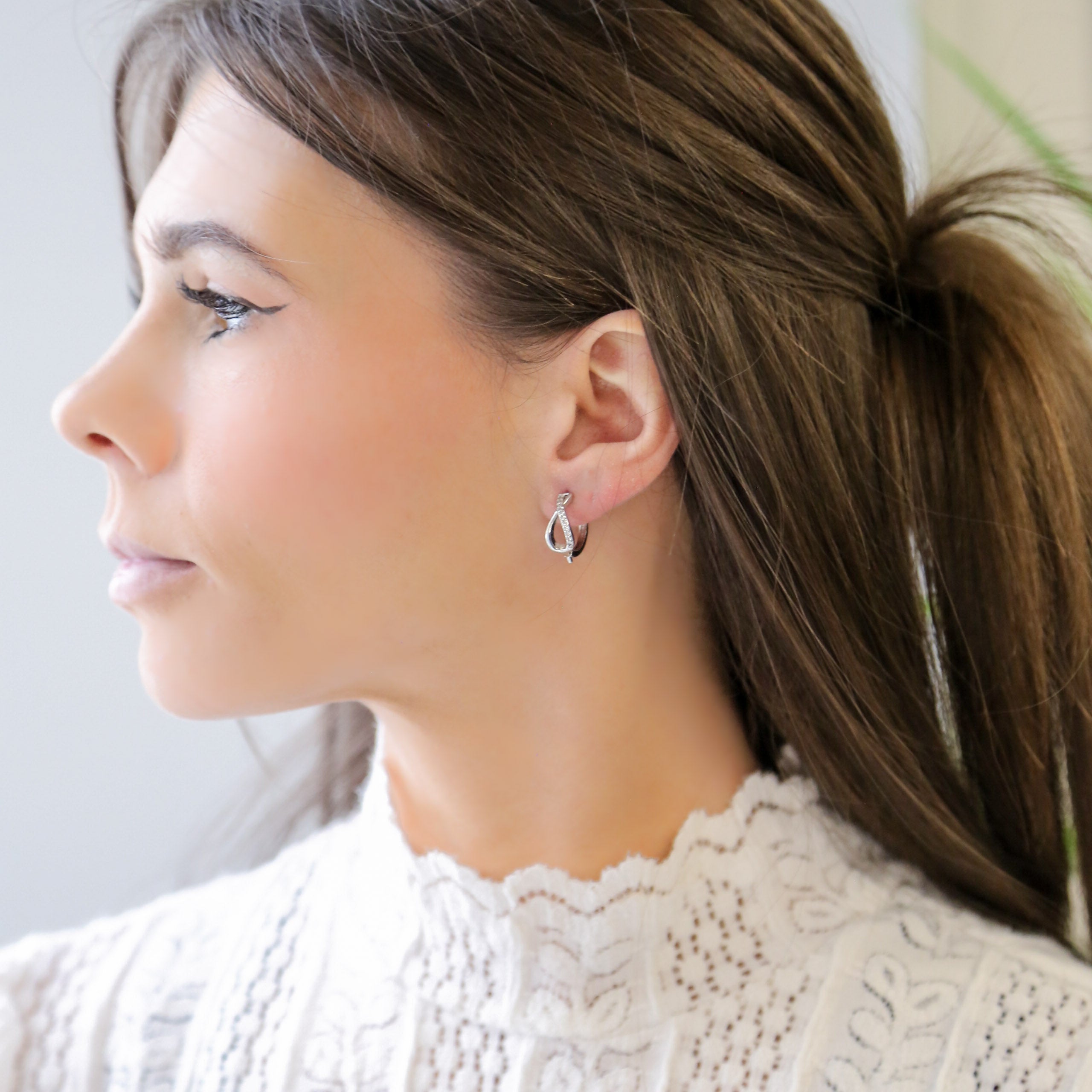 a woman wearing a pair of silver hoop earrings