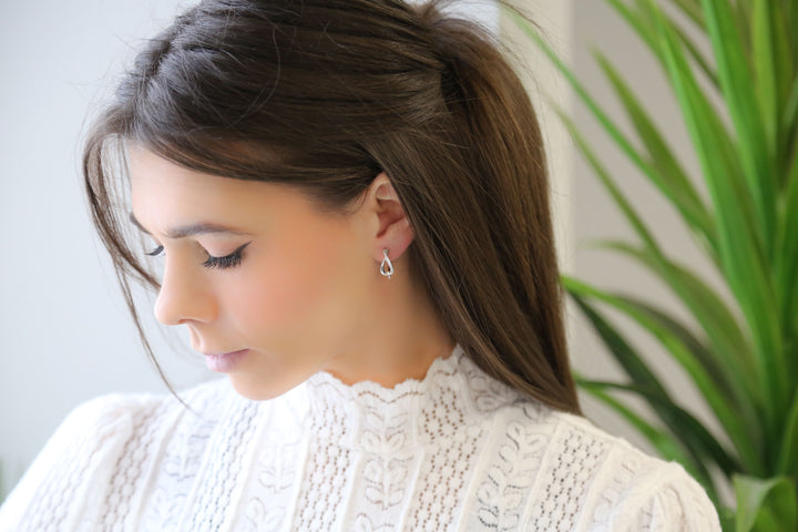 a woman in a white blouse looking down at her cell phone