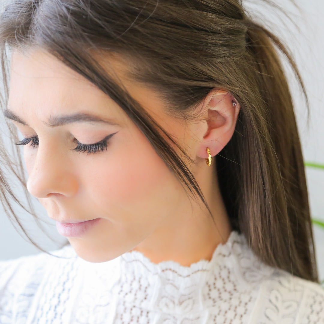 a woman wearing a pair of gold earrings