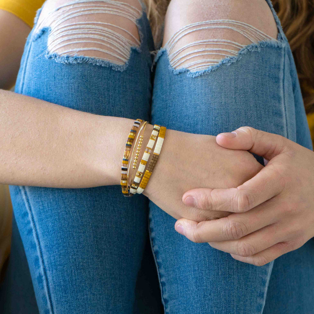 a woman wearing a bracelet and jeans sitting on a couch