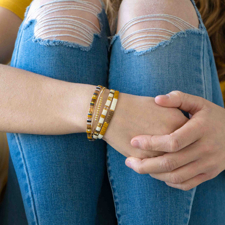 a woman wearing a bracelet and jeans sitting on a couch