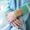 a woman wearing a stack of bracelets on her wrist
