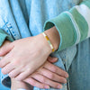 a person wearing a gold bracelet and a blue jean jacket