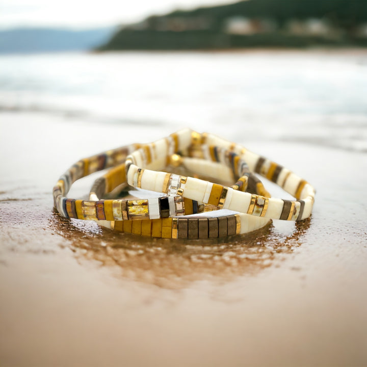 a couple of bracelets sitting on top of a sandy beach