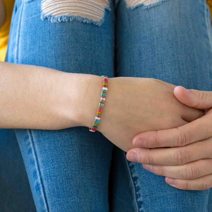 a woman wearing a bracelet with a colorful bead