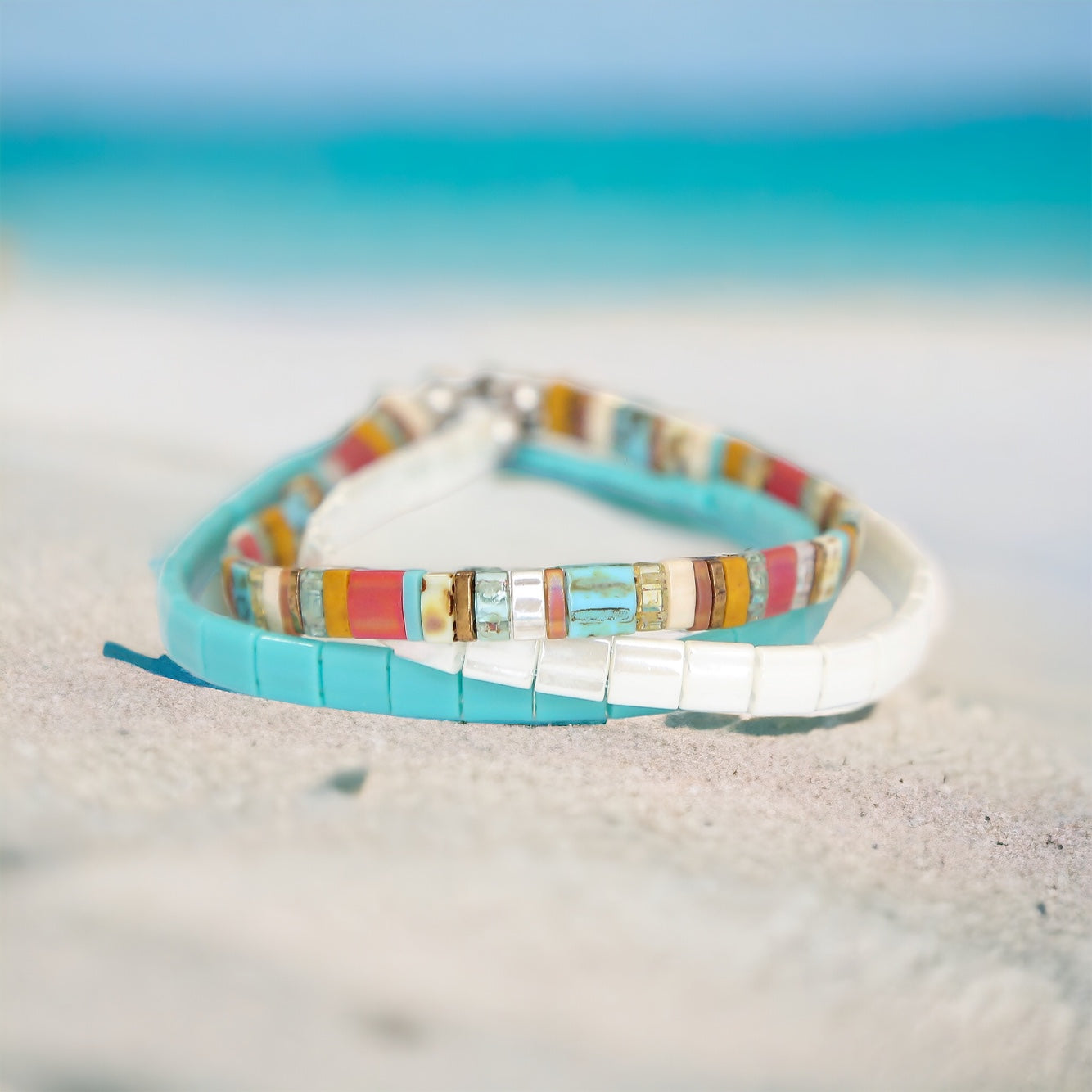 a couple of bracelets sitting on top of a sandy beach