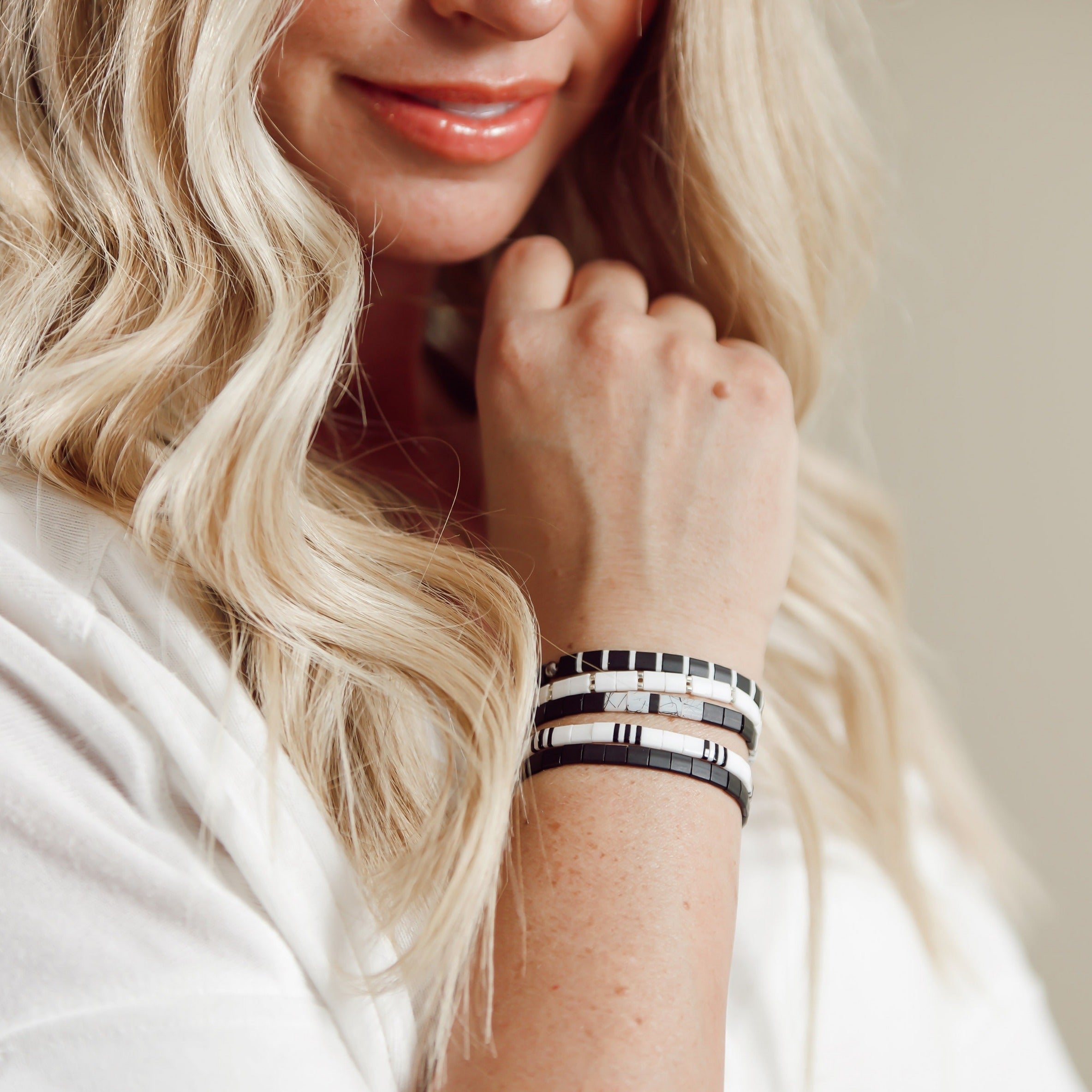 a woman wearing a white shirt and a black and white bracelet