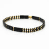 a black and gold beaded bracelet on a white background