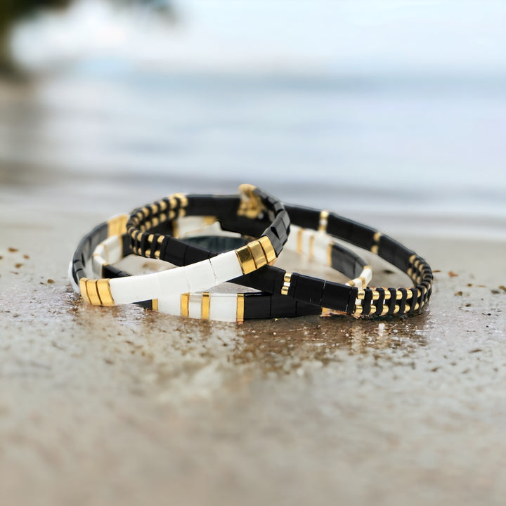 a couple of bracelets sitting on top of a sandy beach