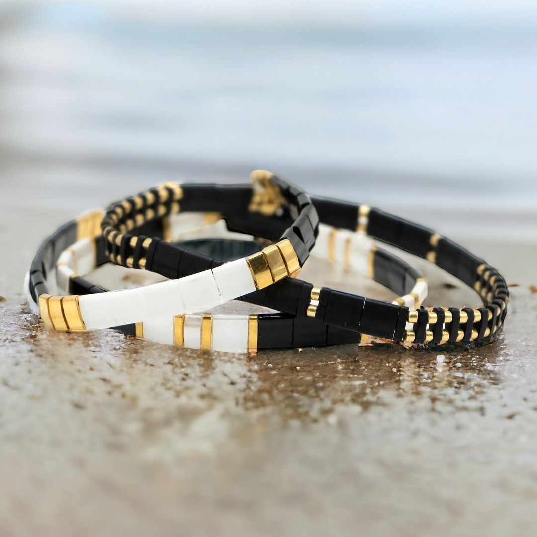 a couple of bracelets sitting on top of a sandy beach