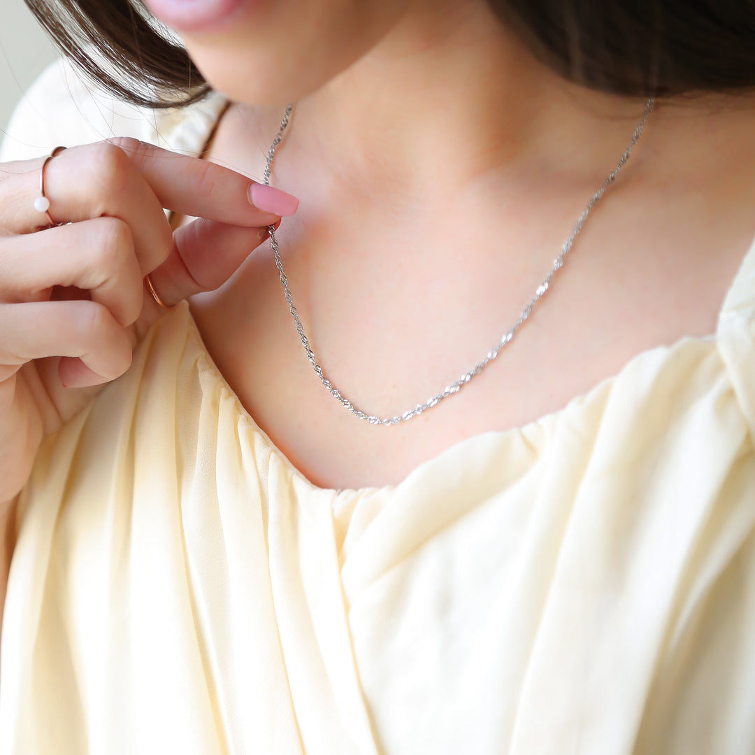 a woman in a white dress holding onto a necklace